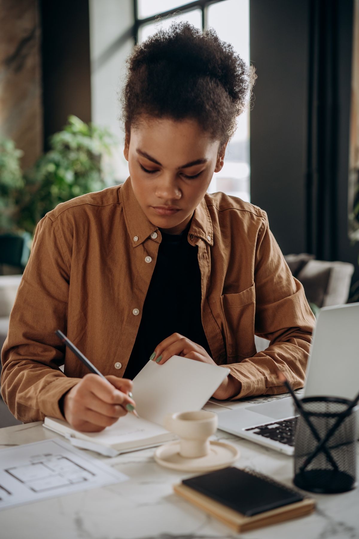 Young woman writing out a budget at her desk